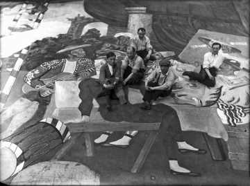 19_Pablo_Picasso_and_scene_painters_sitting_on_the_front_cloth_for_Parade_(Ballets_Russes)_at_the_Theatre_du_Chatelet,_Paris,_1917,_Lachmann_photographer